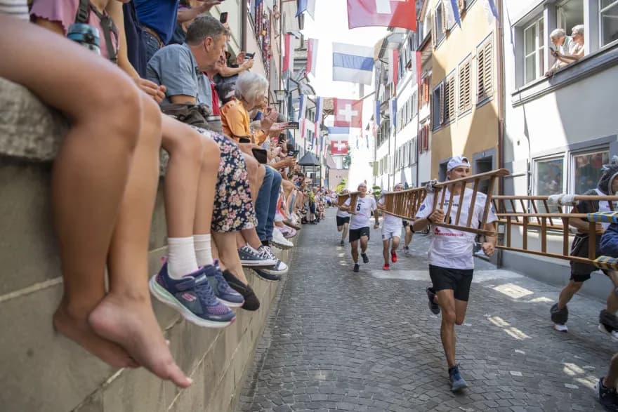 Teilnehmer rennen mit Leitern durch die Zuger Altstadt beim Chriesisturm